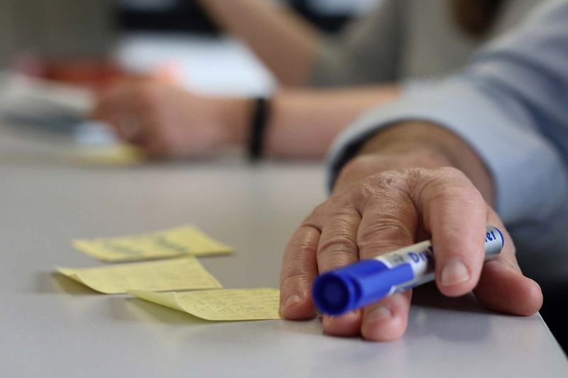 A mans hand resting on a table top with a pen in his hand